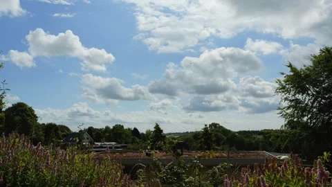 Fluffy white clouds moving over a green landscape Video stock 338072131
