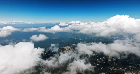 Fluffy white clouds roll over jagged mountain peaks Stock Footage 303316473