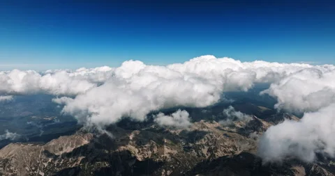 Fluffy white clouds roll over jagged mountain peaks Stock Footage 303317528