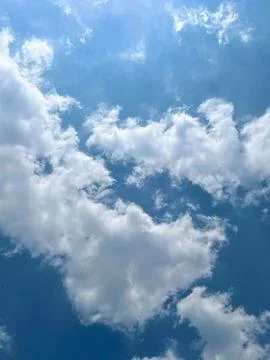 Fluffy white clouds scattered across a vibrant blue sky on a bright sunny day Stock Photos