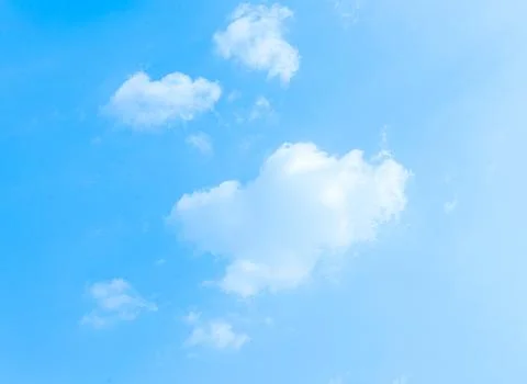 Fluffy white clouds scattered across a clear bright blue sky during daytime Stock Photos