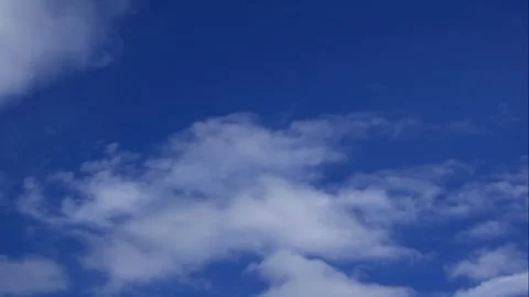 Fluffy white clouds slowly drift across a bright blue sky in smooth motion Stock Footage 320812266