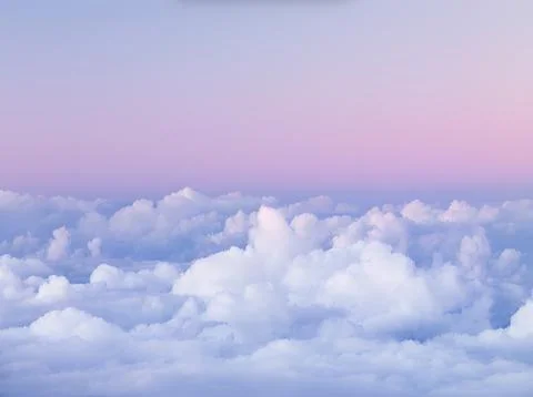 Fluffy white clouds under a purple and pink sunset sky Stock Photos