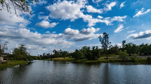 Fluffy White Clouds, Wind and Dappled Sunlight over Pretty Lake Time Lapse Stock Footage 281000267