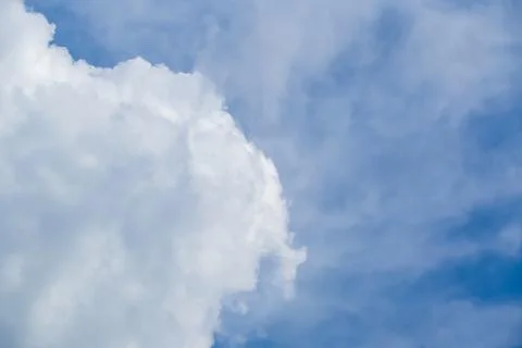 Fluffy white cumulus cloud in bright blue sky with copy space Stock Photos