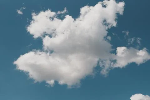 Fluffy White Cumulus Cloud Drifting in Clear Vibrant Blue Sky Symbolizing F.. Stock-Fotos