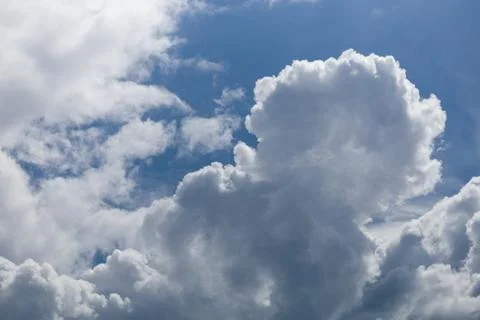 Fluffy white cumulus clouds against a clear blue sky, natural weather background Stock Photos