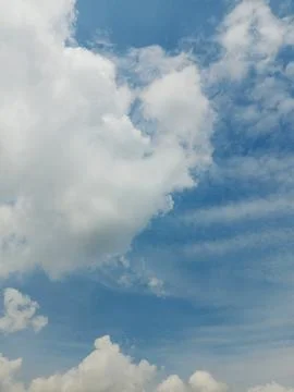 Fluffy white cumulus clouds in a bright blue sky Stock Photos