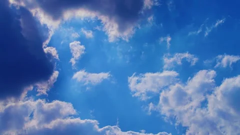Fluffy white cumulus clouds drift across a bright clear blue sky on a peaceful s Stock Footage 328827401