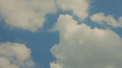 Fluffy white cumulus clouds drifting across a bright blue sky on a clear day Stock Footage 344643981