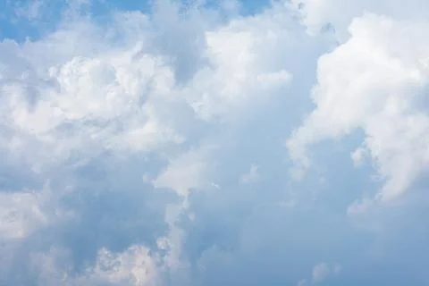 Fluffy white cumulus clouds drifting across a bright blue summer Stock Photos