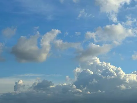 Fluffy white cumulus clouds float across a vibrant blue sky on a summer day Foto stock