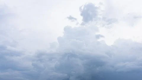 Fluffy white cumulus clouds float across a bright daylight sky blue atmospher Stock Photos