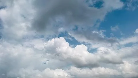 Fluffy white cumulus clouds floating in a bright blue sky on a sunny day Stock Photos