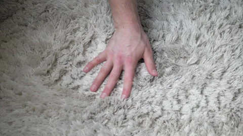 A fluffy white rug is stroked by hand in slow motion. Top view. Warm shag carpet Stock Footage 279825367