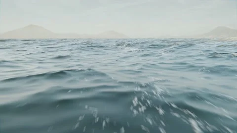 Flug über Wasser oder Ozean mit Wellen und Land am Horizont Stock Footage