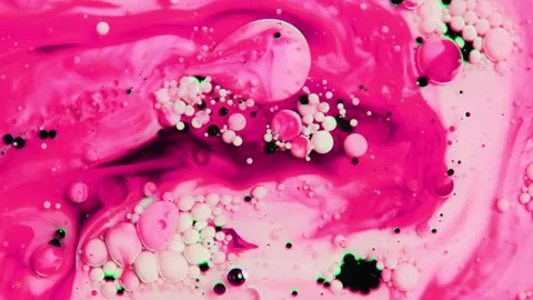 Fluid motion of pink ink drops mixing with white liquid substance Stock Footage 327575534