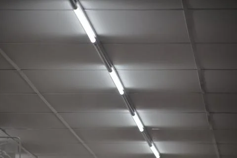 Fluorescent ceiling lights illuminating office space, creating geometric pa.. Stock Photos