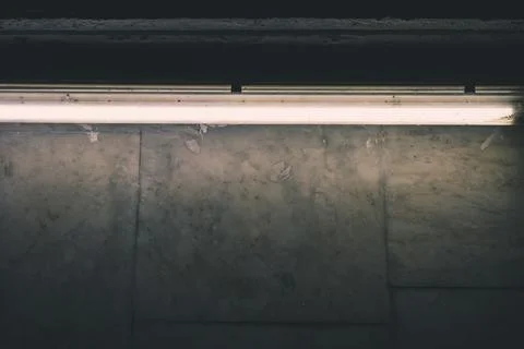 A fluorescent lamp illuminates a marble wall in the subway Stock Photos