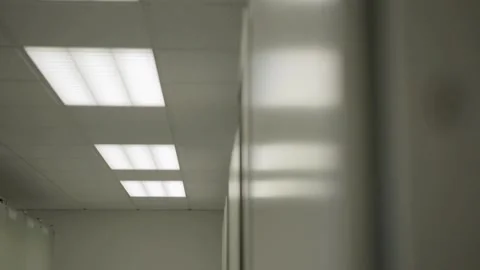Fluorescent office lights flicker on and off in an empty hallway Stock Footage 280190297