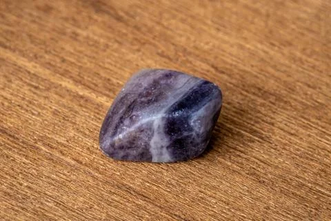 Fluorite precious gemstone with smooth surface purple and grey tones on woode Stock Photos