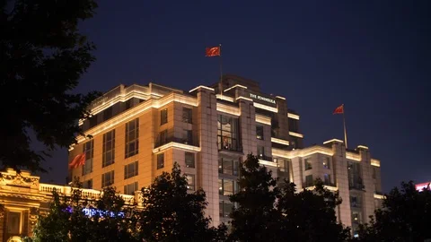 Fluttering Red Chinese Flags on The Peninsula Hotel, Shanghai Bund at Nighttime Stock Footage 121195218