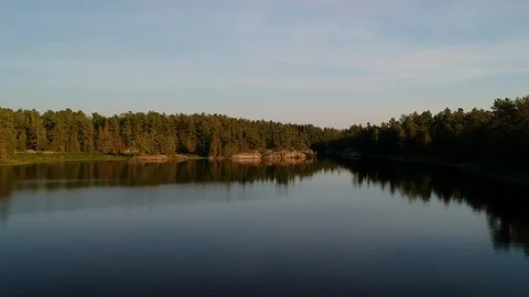 Fly up above calm lake with reflections revealing endless boreal forest Stock Footage 112229058