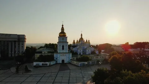 Fly above tree crowns to St. Michael's Golden-Domed Monastery at the banks of Stock Footage 201007016