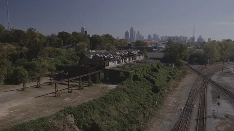Fly along train tracks decaying building and Atlanta skyline Stock Footage 82448004