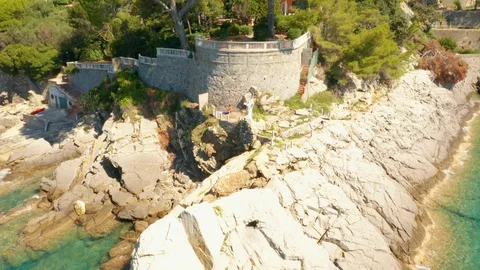 Fly around a white Jesus statue on the rocky hill in Ligurian Sea. A beach with Stock Footage 129046469