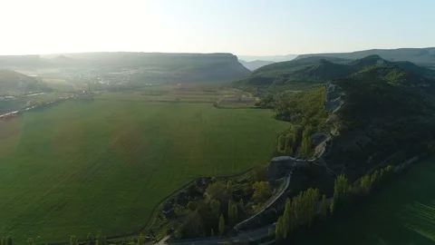 Fly back with a view of the field, hills, road and passing car. Sunset. Crimea. Stock Footage 125411824