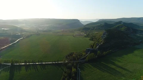 Fly back with a view of the field, hills, road and passing car. Sunset. Crimea. Stock Footage 125411839