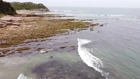 Fly backwards over rocks &amp; water in playa de Oyambre, Cantabria, Spain 4K P1 Video stock 155598728