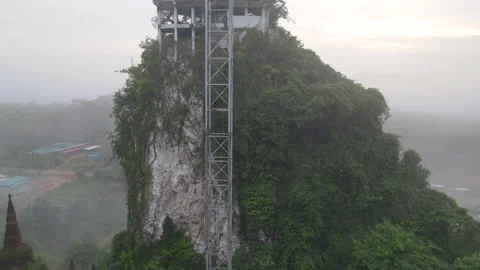 Fly from down and go up along rocky mountain with pagoda on top and stay over Stock Footage 142079512