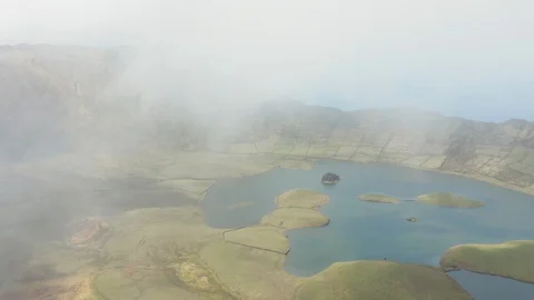 Fly down from a cloud above green caldera with lake in the middle. Aerial of Stock Footage 119891973