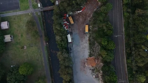 Fly drone over green grass and trees with driveway next to tram Stock Footage 83023560