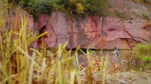 A fly fisherman wading waist deep in the river casts his line deeper into the ri Stock Footage 141210853