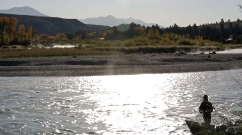 Fly fishermen float down an Idaho river in a driftboat as sun is reflected off Stock Footage 36318646