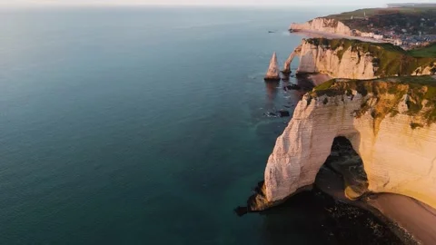 Fly into golden hour at Étretat. Dramatic cliffs and arches shine at sunset in Stock Footage 318648647