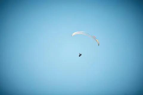 Fly High. Keep soaring. a unrecognizable person paragliding in the sky. Stock Photos
