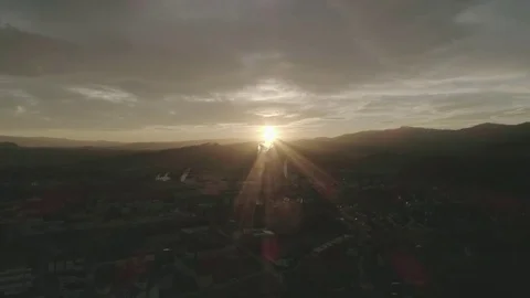 Fly in the last sun rays over a small industrial town in the green valley, 4K Stock Footage 73771045