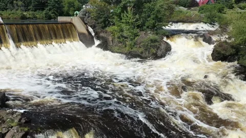 Fly low over a raging river near an over-flow dam on a sunny day-aerial Stock Footage 161332398
