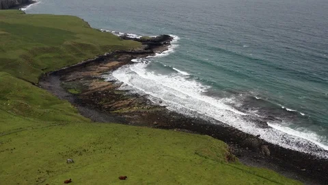 Fly over a beach with waves crushing on Isle of Skye from over a meadow 스톡 동영상 116048911
