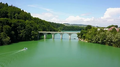 Fly over bridge on beautiful idyllic turquoise lake with boat in foreground Stock Footage 128730420