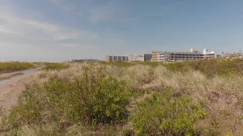 FLY OVER DUNES TOWARD HOTELS Stock Footage