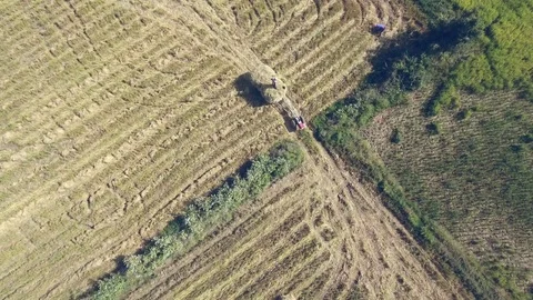 Fly over a farmer loading stack of hay on top of a tractor trailer Vídeos de archivo 122045185