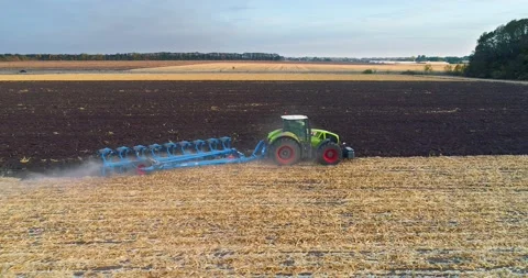 Fly over the field with a tractor. Tractor plows the field aerial view. The Stock Footage 145127174