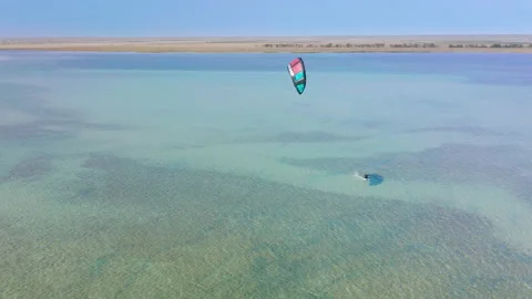 Fly over from a height of a kitesurfer trying to get to his feet and catch a Stock Footage 156041596