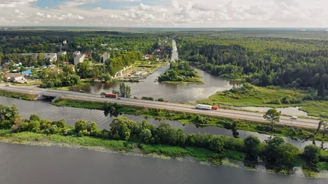 Fly over a highway across a river with a small town and forest trees Stock Footage 109607082