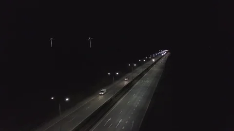 Fly over the highway at night, the wind turbines are spinning on the background Stock Footage 115924246